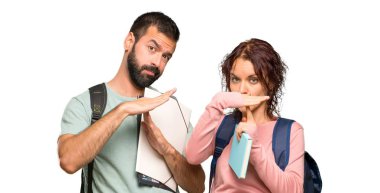 Sırt çantaları ve kitapları ile izole beyaz arka plan üzerinde bir hareket durdurmak için eliyle stop jest yapma iki öğrenci