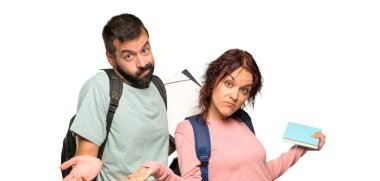 Sırt çantaları ve kitapları olan iki öğrenci, izole beyaz arka plan üzerinde omuz kaldırırken şüphe jesti yapıyor