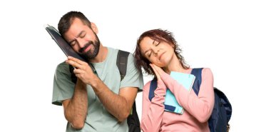 Sırt çantaları ve uyku hareketi yapan kitapları olan iki öğrenci. İzole beyaz arka plan üzerinde sevimli tatlı ifade