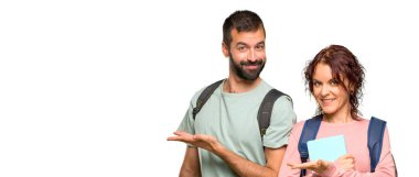 Izole beyaz arka plan üzerinde gülümseyerek bakarken bir fikir sunan sırt çantaları ve kitapları ile iki öğrenci