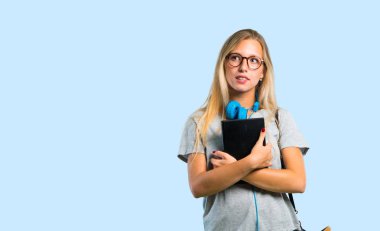 Gözlüklü öğrenci kız şüpheleri olan ve dudak ısırırken yüz ifadesini karıştırarak. Mavi arka plan la ilgili bir fikri sorgulama