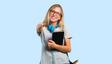 Mavi arka planda gülümserken gözlüklü öğrenci kız sizi işaret ediyor