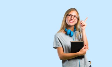 Gözlüklü öğrenci kız işaret parmağı ile işaret harika bir fikir ve mavi arka plan üzerinde bakarak