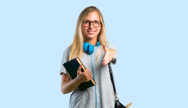 Mavi arka plan üzerinde iyi bir anlaşma kapanış için el sıkışma gözlük ile Öğrenci kız