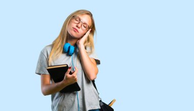 Gözlüklü öğrenci kız uyku hareketi yapıyor. Mavi arka planda sevimli ve tatlı ifade