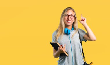 Sarı arka plan üzerinde bir parmak kaldırırken çözüm gerçekleştirmek niyetinde gözlüklü öğrenci kız