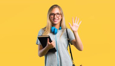 Gözlüklü öğrenci kız sarı arka planda parmakları ile beş sayma