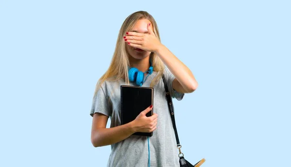 Student girl with glasses covering eyes by hands. Do not want to see something on blue background