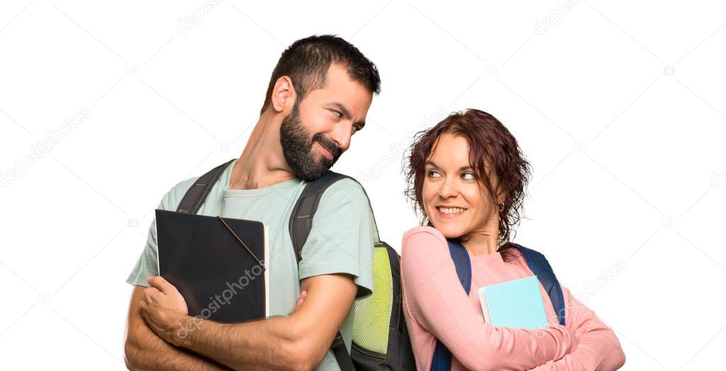 Two students with backpacks and books looking over the shoulder with a smile on isolated white background