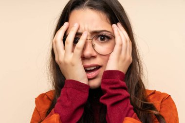 Gözleri kaplayan ve parmaklardan bakan paltolu genç kız