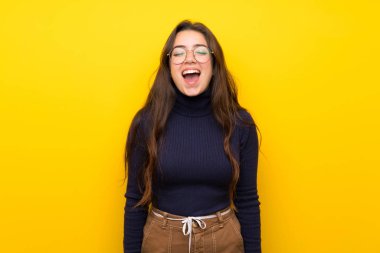 Ağzı tamamen açık ön bağırarak izole sarı duvar üzerinde Genç kız