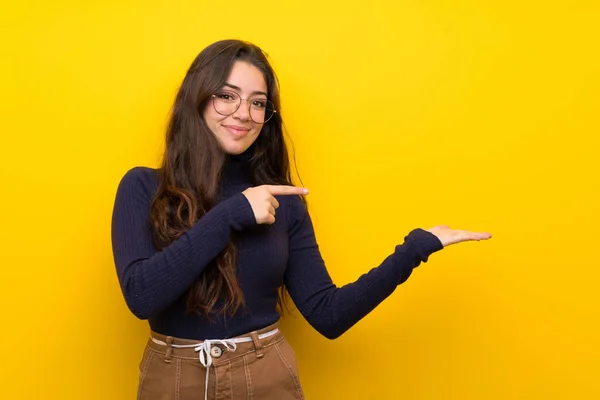 Tiener Meisje Geïsoleerde Gele Muur Holding Copyspace Denkbeeldige Palm Een — Stockfoto