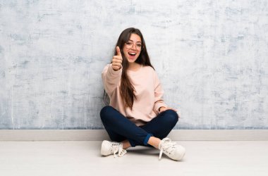 Genç öğrenci kız iyi bir şey oldu çünkü thumbs up bir masada okuyor