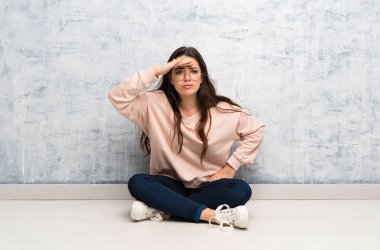 Bir masada okuyan genç öğrenci kız bir şey bakmak için el ile uzak bakıyor