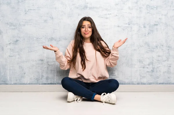 Genç öğrenci kız ellerini kaldırırken şüpheleri olan bir masada okuyan