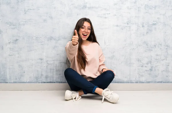 Genç öğrenci kız iyi bir şey oldu çünkü thumbs up bir masada okuyor