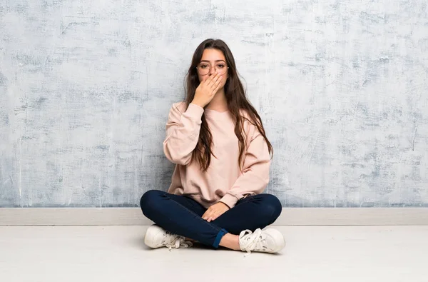 Genç öğrenci kız elleri ile ağız kapsayan bir masada okuyan