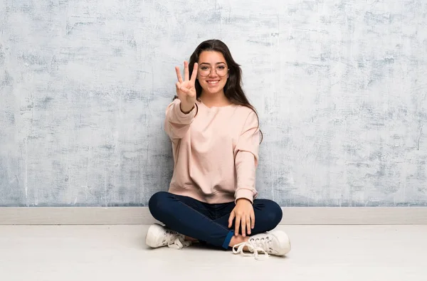 Genç öğrenci kız mutlu bir masada okuyan ve parmakları ile üç sayma