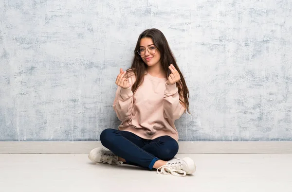 Genç öğrenci kız para jest yapma bir tabloda okuyan