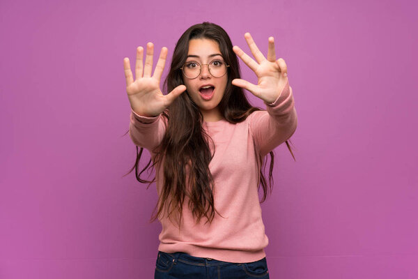 Teenager girl over purple wall counting nine with fingers