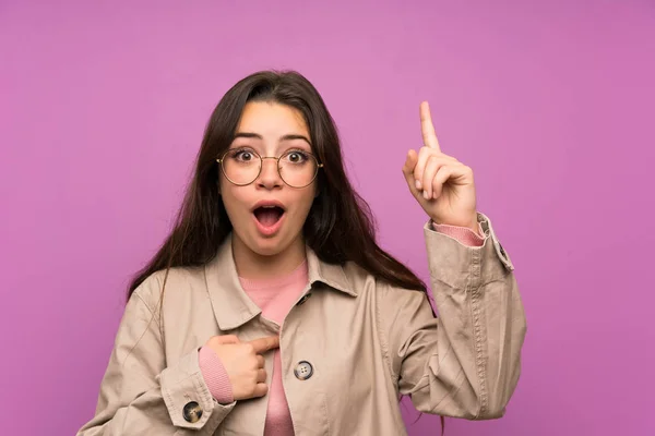 Teenager girl over purple wall with surprise facial expression