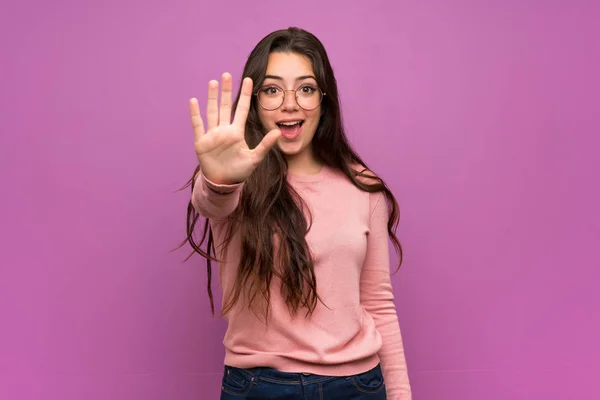 Дівчина Підліток Над Фіолетовою Стіною Підраховує Ять Пальцями — стокове фото