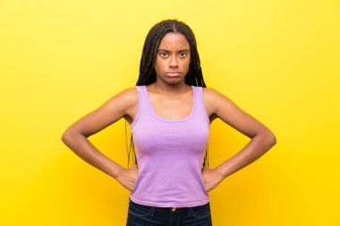 Izole sarı duvar kızgın üzerinde uzun örgülü saçlı Afrikalı-Amerikalı genç kız