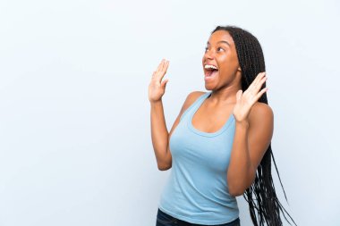 Şaşırtıcı yüz ifade ile izole mavi arka plan üzerinde uzun örgülü saç ile Afrikalı Amerikan Genç kız