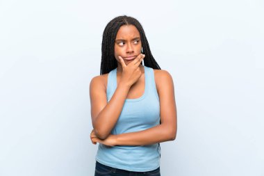 Uzun örgülü saç ile Afrika Amerikan Genç kız izole mavi arka plan düşünme bir fikir