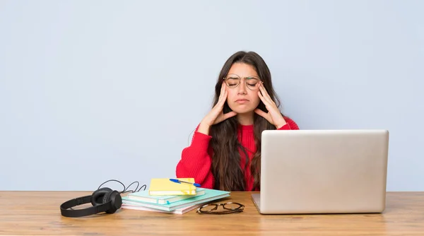 Teenager student girl studying in a table with headache