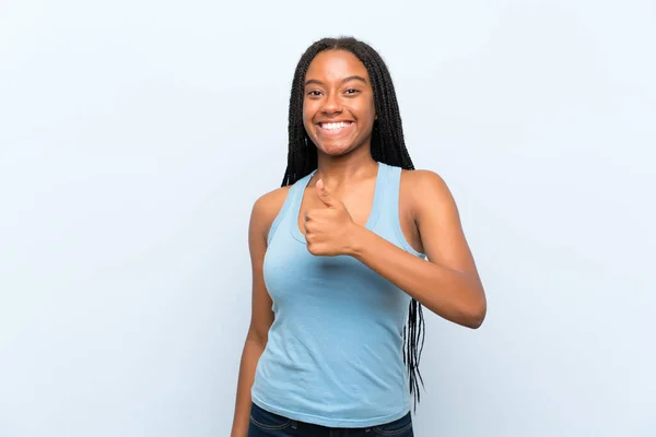 非洲裔美国少女与长辫子的头发在孤立的蓝色背景给一个竖起大拇指的手势 — 图库照片