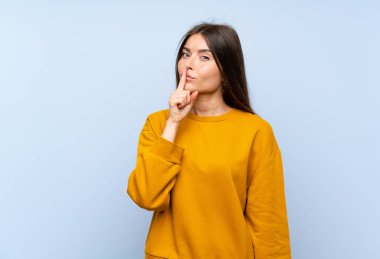 Izole mavi duvar üzerinde kafkas genç kadın sessizlik jestyapıyor