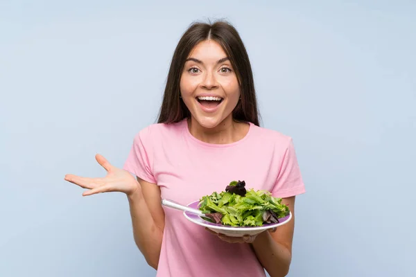 Jonge Vrouw Met Salade Geïsoleerde Blauwe Achtergrond Met Geschrokken Gezichtsuitdrukking — Stockfoto