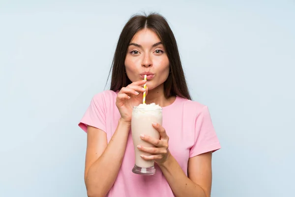 Mujer joven con batido de fresa sobre fondo azul aislado —  Fotos de Stock