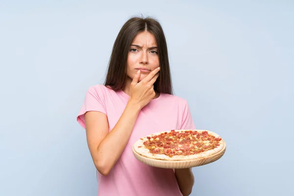 Bastante Joven Sosteniendo Una Pizza Sobre Una Pared Azul Aislada — Foto de Stock