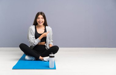 Genç spor kadın yan parmak işaret mat ile katta oturan