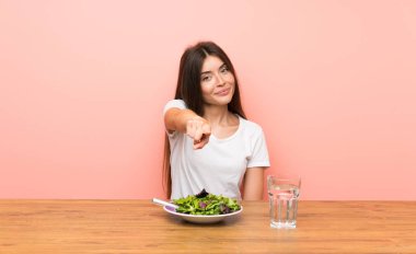 Kendine güvenen bir ifade ile bir salata puan parmak ile genç kadın