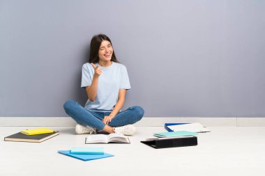 Zeminüzerinde birçok kitap ile genç öğrenci kadın size parmak