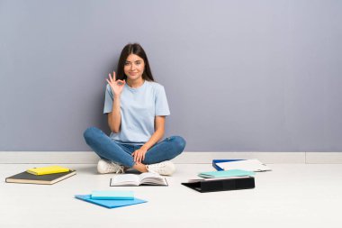 Parmakları ile ok işareti gösteren katta birçok kitap ile genç öğrenci kadın