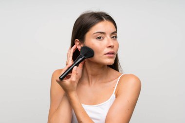 İzole gri arka plan üzerinde makyaj fırçası ile Pretty genç kadın