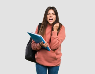 Genç öğrenci kadın tecrit gri arka plan üzerinde kötü bir durum tarafından sinirli defterleri tutan