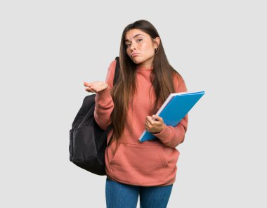 İzole gri arka plan üzerinde bir şey anlamak için mutsuz deftertutan genç öğrenci kadın