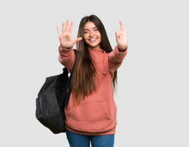 İzole gri arka plan üzerinde parmakları yla yedi sayma defterleri tutan genç öğrenci kadın