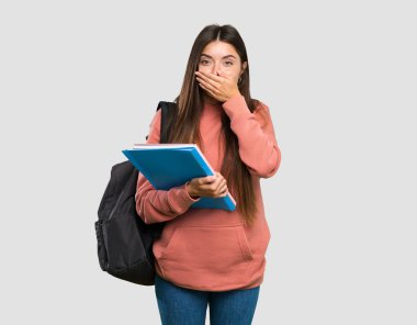 Genç öğrenci kadın izole gri arka plan üzerinde elleri ile ağız kapsayan deftertutan