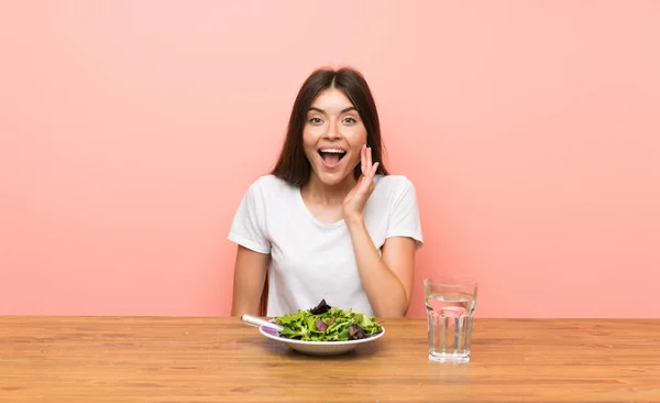 Young woman with a salad with surprise and shocked facial expression