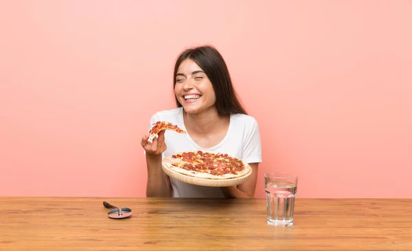 Mujer joven con una pizza en una mesa — Foto de Stock