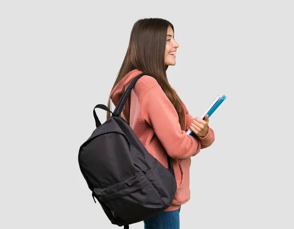 Joven Estudiante Sosteniendo Cuadernos Posición Lateral Sobre Fondo Gris Aislado — Foto de Stock