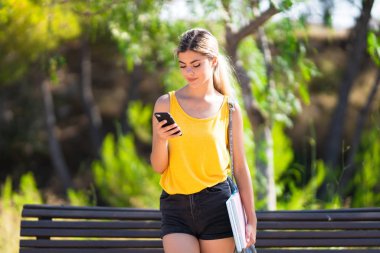 Cep telefonu kullanarak açık havada genç genç öğrenci kız