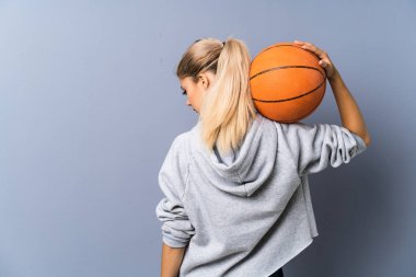 Genç kız gri duvar üzerinde basketbol oynuyor