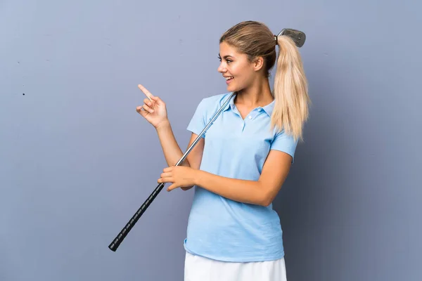 青少年高尔夫球手女孩在灰色的墙壁惊讶 并指着一边手指 — 图库照片